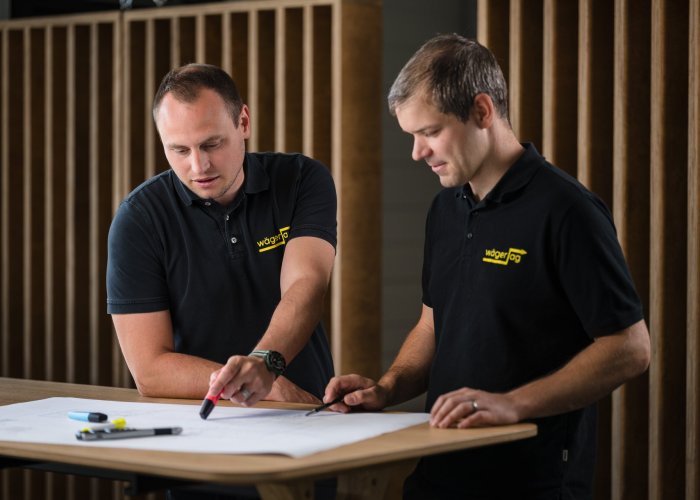 Zwei Mitarbeitende besprechen Installationspl&auml;ne und koordinieren ein Elektroprojekt.