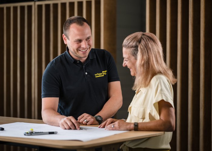Beratungsgespr&auml;ch zu Elektroinstallationen mit Kundin und Fachperson anhand eines Installationsplans.