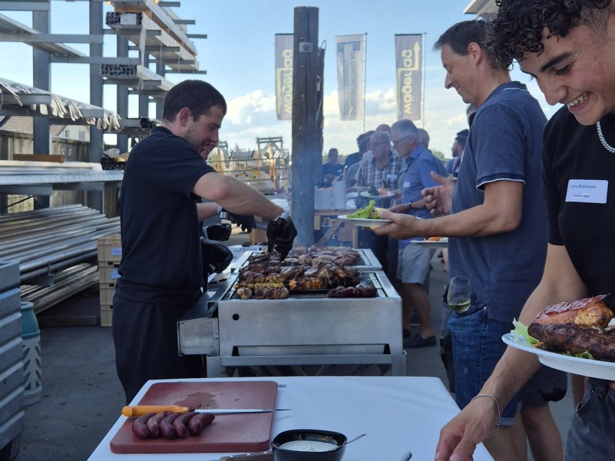 Mitarbeitende der Elektro W&auml;ger AG bedienen sich am Grillbuffet mit frisch gegrilltem Fleisch