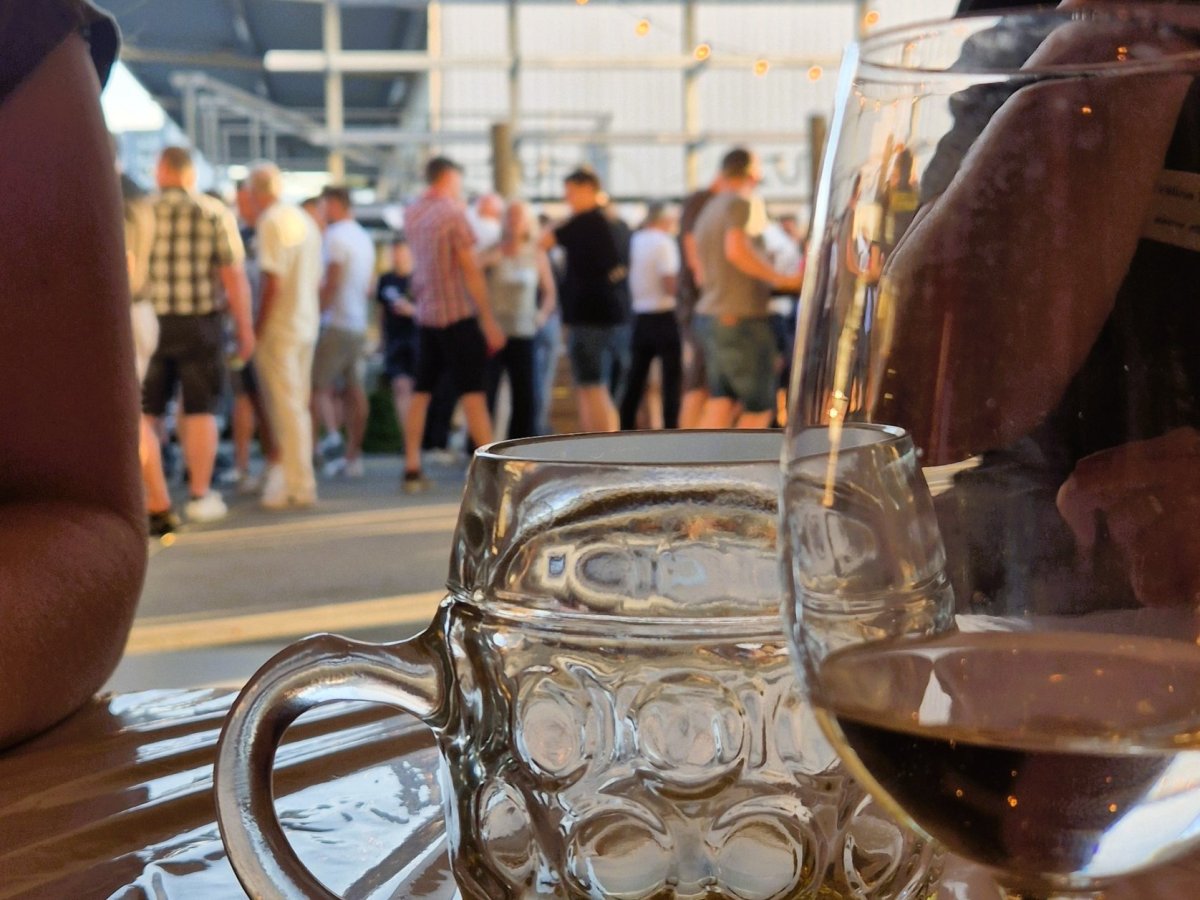 Bier- und Weinglas im Vordergrund eines Firmenanlasses der Elektro W&auml;ger AG mit Mitarbeitenden im Hintergrund