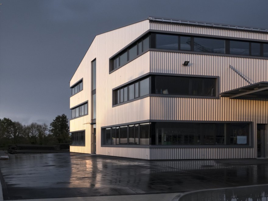 Aussenansicht des Firmengeb&auml;udes der Elektro W&auml;ger AG mit Fahnen bei Abendd&auml;mmerung
