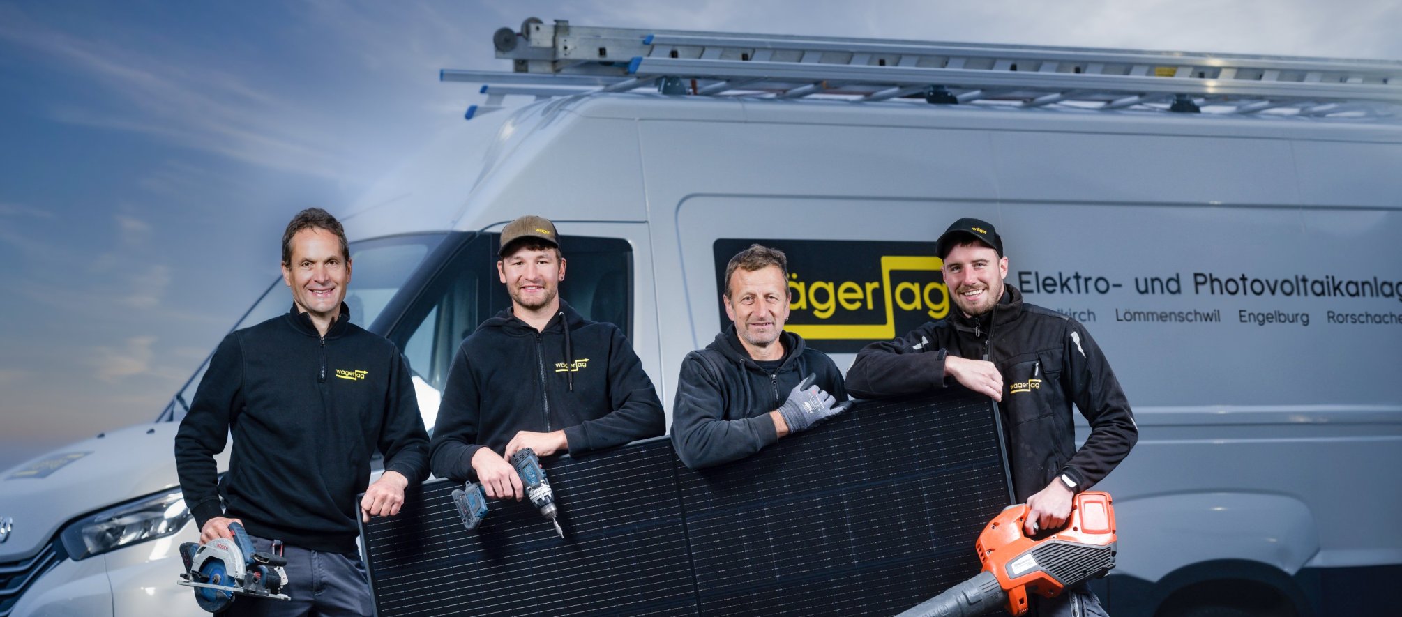 Vier Mitarbeitende der Elektro W&auml;ger AG mit Photovoltaikmodul vor Firmenfahrzeug