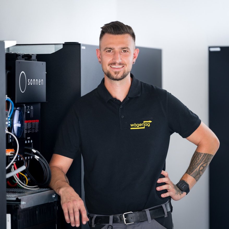 Mitarbeiter steht vor einem Batteriespeicher für das Personalfoto