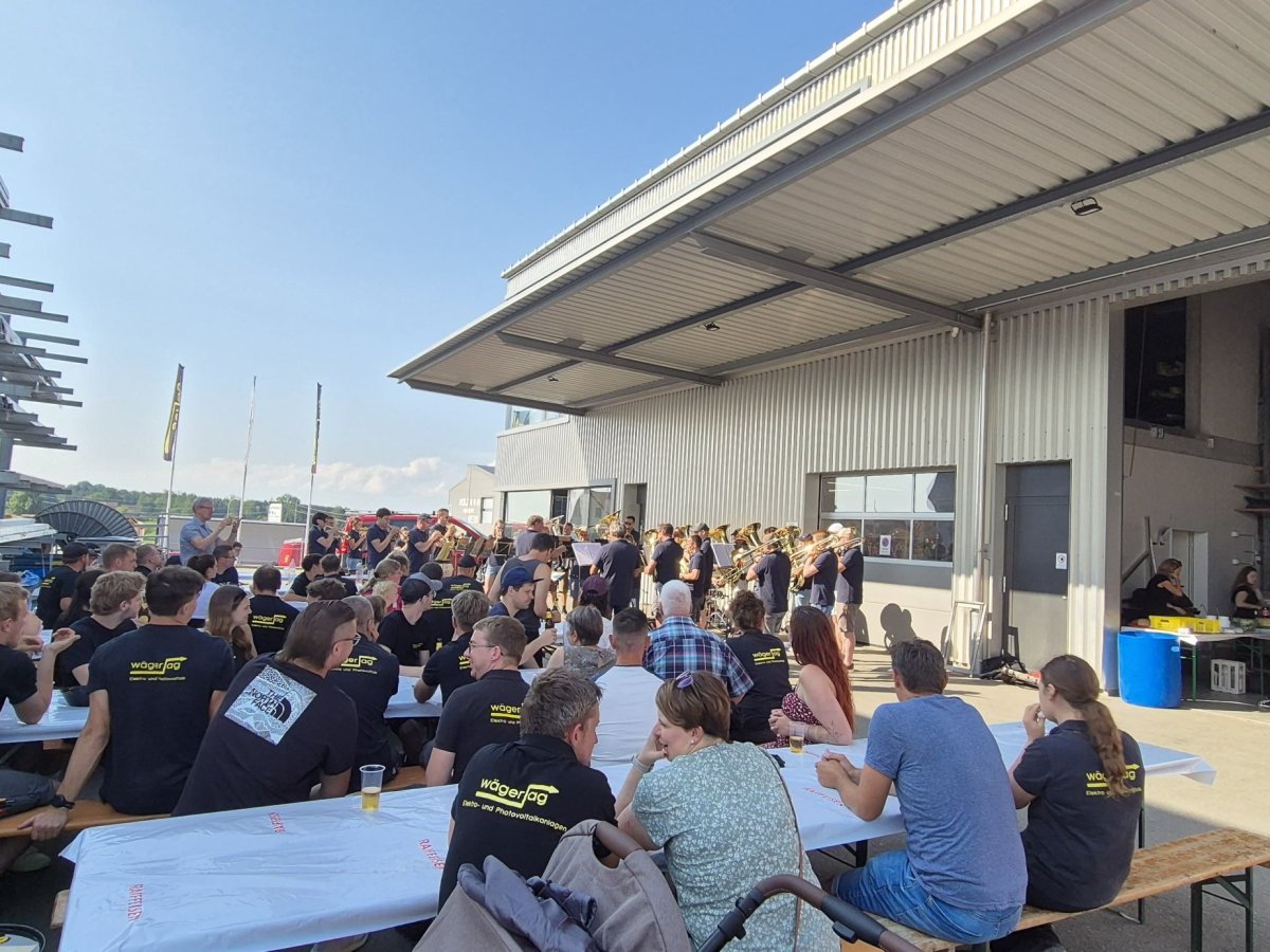 Mitarbeitende der Elektro W&auml;ger AG h&ouml;ren beim Grillfest der Musikgesellschaft Bernhardzell zu
